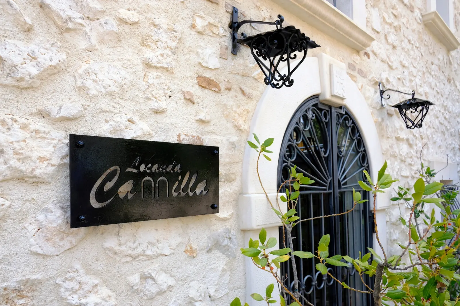 Insegna in ferro battuto Locanda Camilla accanto all'ingresso ad arco